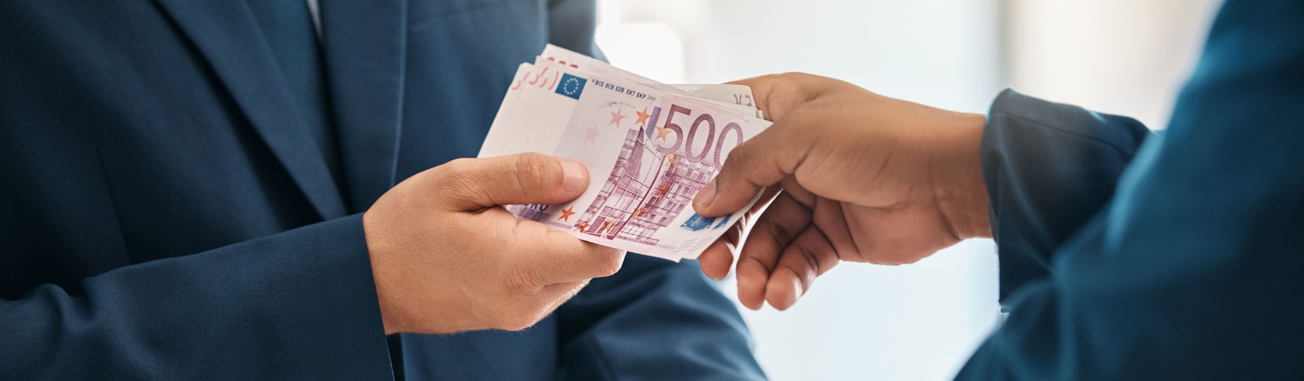 due uomini d'affari si stringono la mano e si passano del denaro